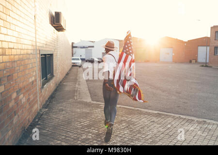 Back view of young man running with American flag at backlight Stock Photo