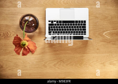 Laptop and poppy in flower vease on wood, top view Stock Photo