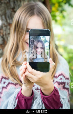 Portrait of laughing girl taking selfie with cell phone Stock Photo