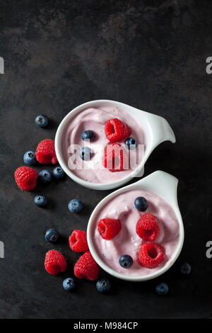 Two bowls of fruit yoghurt with blueberries and raspberries on dark ground Stock Photo