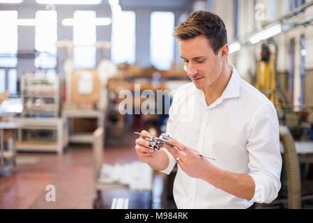 Young businessman in factory holding component Stock Photo