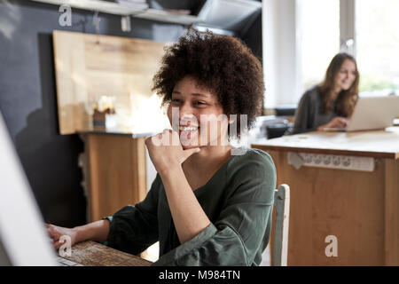 Happy young woman using computer in modern office Stock Photo