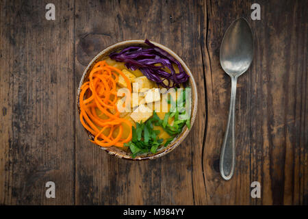 Turmeric curry dish with carrot, tofu, red cabbage and parsley in bowl Stock Photo