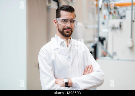 Portrait of man wearing lab coat and safety goggles in factory Stock Photo