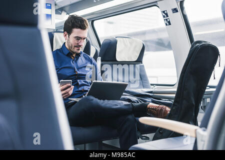 Businessman working in train using laptop Stock Photo