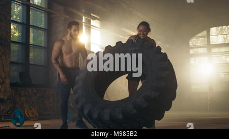 Fit Athletic Woman Lifts Tire Under Supervision of Her Partner/ Trainer, as Part of Her Cross Fitness/ Bodybuilding Gym Training. She Gives High Five  Stock Photo