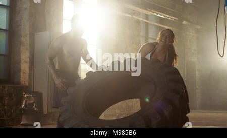 Fit Athletic Woman Lifts Tire Under Supervision of Her Partner/ Trainer, as Part of Her Cross Fitness/ Bodybuilding Gym Training. She Gives High Five  Stock Photo