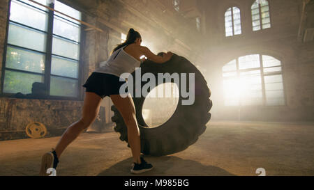 Fit Athletic Woman Lifts Tire as Part of Her Cross Fitness/ Bodybuilding Training. Stock Photo