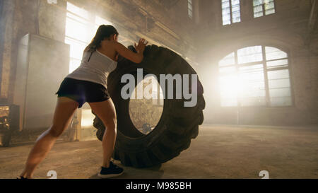 Fit Athletic Woman Lifts Tire as Part of Her Cross Fitness/ Bodybuilding Training. Stock Photo