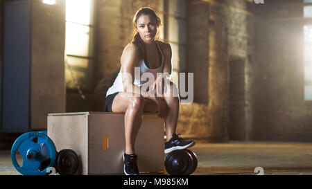 Beautiful Athletic Woman Uses Smartphone For Tracking Her Intensive Cross Fitness Bodybuilding Exercise Program at Her Favourite Gym. Stock Photo