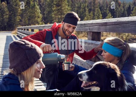 Group of friends with dog hiking resting on a bridge Stock Photo