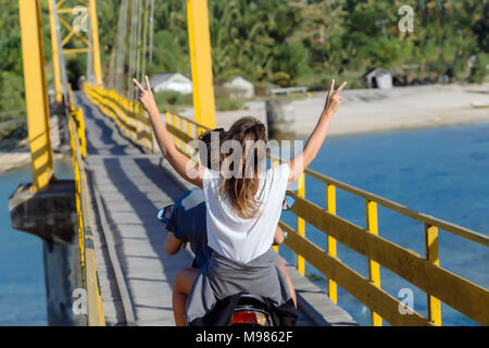 Indonesia, Bali, Lembongan island, carefree young couple riding motor scooter on a bridge Stock Photo