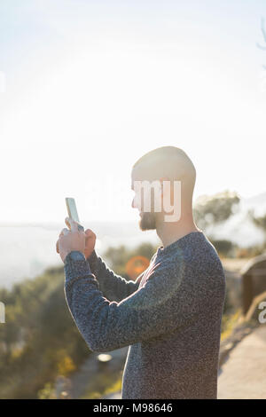 Smiling young man holding cell phone in backlight Stock Photo