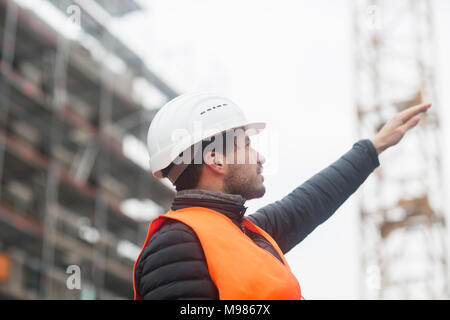 Man with wearing safety vest and hard hat at construction site Stock Photo