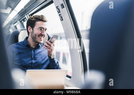 Happy businessman in train using cell phone Stock Photo