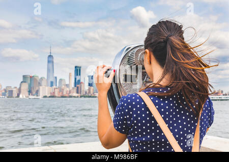 USA, New York, woman looking at Manhattan skyline with coin-operated binoculars Stock Photo