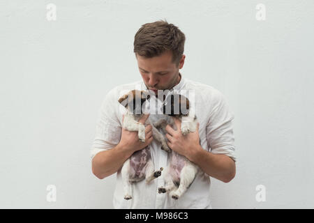 Man holding two small puppies in his hands Stock Photo
