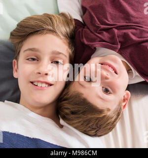 Top view of two smiling brothers lying on bed Stock Photo