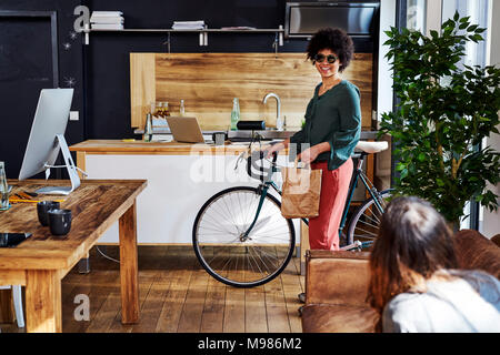 Young woman with bicycle arriving in modern office Stock Photo