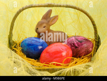 bunny and three painted eggs in easter nest Stock Photo