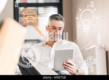 Man sitting in office, using digital tablet to remote-control his smart home Stock Photo