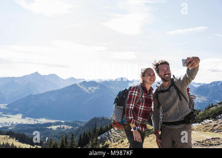 Austria, Tyrol, smiling young couple taking a selfie in mountainscape Stock Photo