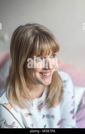 Portrait of laughing woman sitting on bed Stock Photo