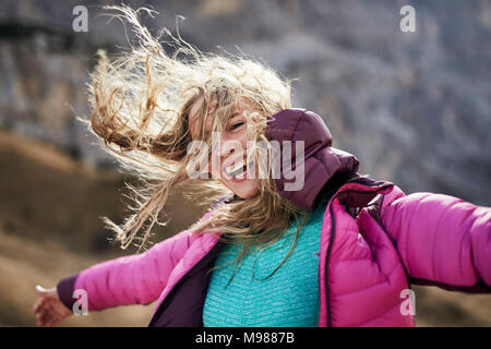 Happy young woman leaning against the wind in the mountains Stock Photo