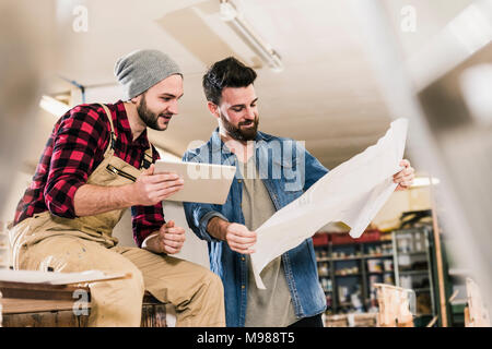 Two men with tablet looking at draft in workshop Stock Photo