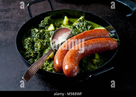 Curly kale with potatoes and two minced pork sausages in pan Stock Photo