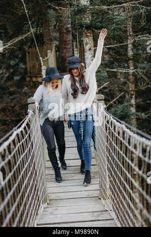Two happy young women walking on a suspension together Stock Photo