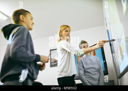 Teacher with students in class at interactive whiteboard Stock Photo