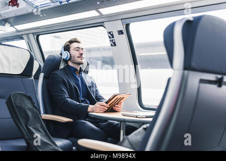 Businessman in train relaxing listening to music Stock Photo
