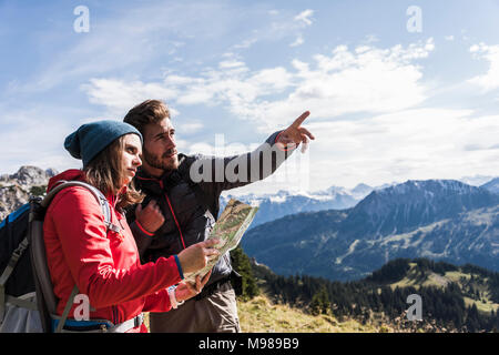 Austria, Tyrol, young couple with map in mountainscape looking around Stock Photo