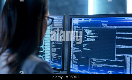 Close-up Shot of Female IT Engineer Working in Monitoring Room. She Works with Multiple Displays. Stock Photo