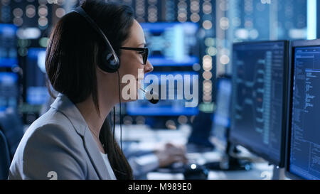 In the System Control Center Woman working in a Technical Support Team Gives Instructions with the Help of the Headsets. Possible Air Traffic Stock Photo