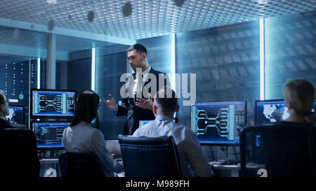 Supervisor Holds Briefing for His Employees in System Control Center Full of Monitors and Servers. Possibly Government Agency Conducts Investigation. Stock Photo