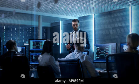 Supervisor Holds Briefing for His Employees in System Control Center Full of Monitors and Servers. Possibly Government Agency Conducts Investigation. Stock Photo