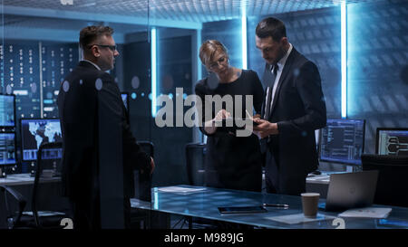 Team of Chief Engineers Have Emergency Meeting in System Controls Center. They Consult Data on Tablet Computer and Analyse it. Computers in the Room Stock Photo