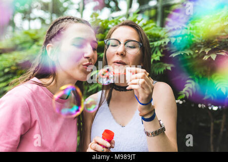 Two teenage girls blowing soap bubbles together Stock Photo