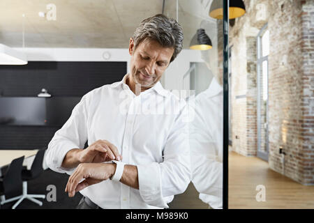 Businessman in conference room using smartwatch Stock Photo