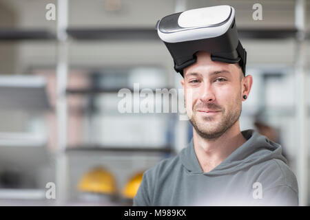 Portrait of smiling young man wearing VR glasses in office Stock Photo