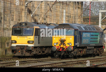 Class 57 diesel electric locomotive in DRS livery and class 92 electric British rail two-tone grey livery wait for their next duty Carlisle station. Stock Photo