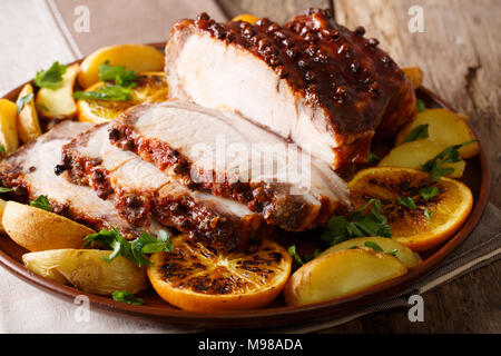 Homemade Hot Pork Tenderloin with Spices with a garnish of potatoes, oranges and apples close-up on a platter. Horizontal Stock Photo