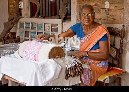 A happy smiling female woman artisan Sri Lankan worker making Beeralu lace weaving items using traditional methods at the The National Museum of Galle Stock Photo