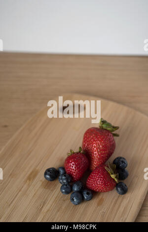 Blueberries and Strawberries on a Bamboo Cutting Board for a Healthy Snack or as Ingredient Preparation Stock Photo