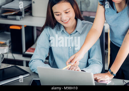 Two asian woman colleagues causal meeting at home office. discuss about business planing at laptop,business teamwork, work mate consulting together Stock Photo