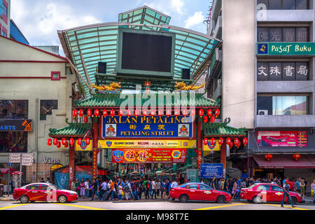 KUALA LUMPUR, MALAYSIA - FEBRUARY 19, 2018: Crowds pass below the main gate of Chinatown at Petaling Street. Famous tourist attraction. Stock Photo