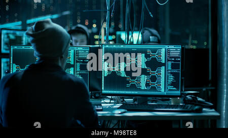 Team of Internationally Wanted Hackers Teem Organizing Advanced Malware Attack on Corporate Servers. Hacker is Working in His Computer. Place is Dark. Stock Photo