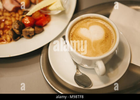 Traditional English breakfast. A cup of coffee with cappuccino is next to it. National food. A world-famous dish that is served in the morning. Stock Photo